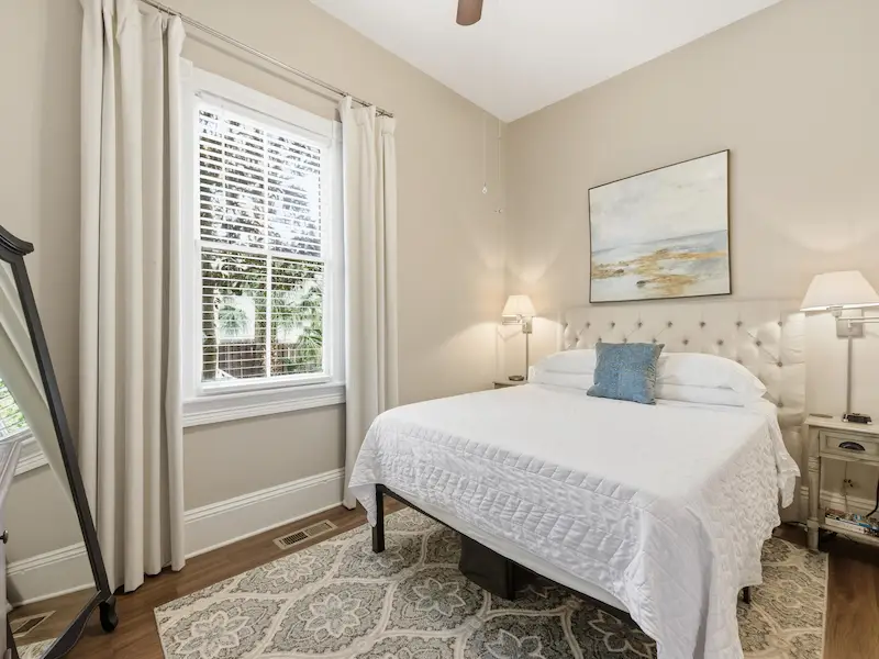 Suite 314A queen bedroom at Savannah vacation rental — white bedding TV dresser hardwood floors