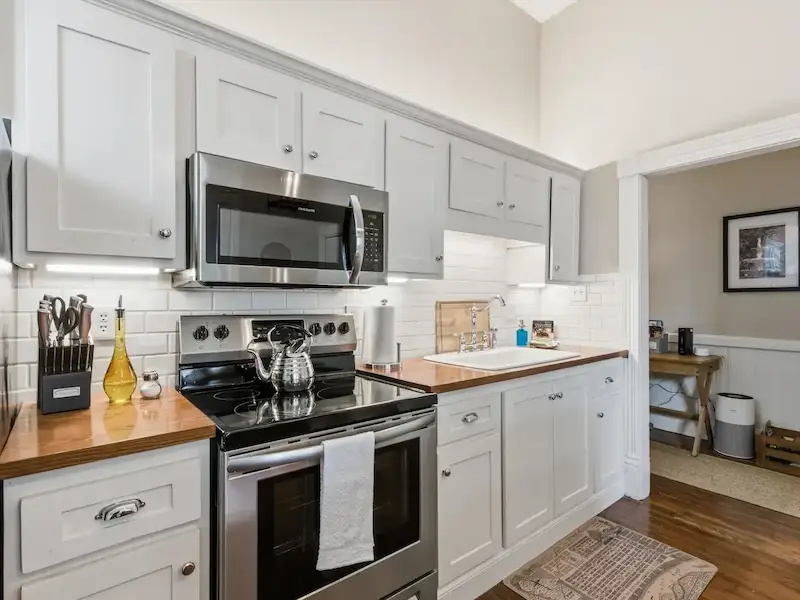 Suite 314A Victorian District Savannah kitchen — stainless steel appliances subway tile white shaker cabinets