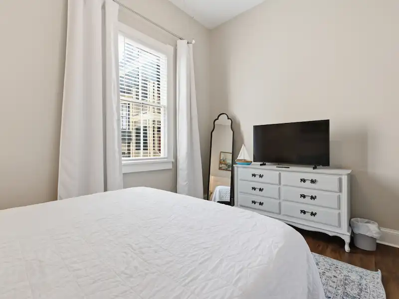 Suite 316A queen bedroom at The Wilder House Savannah — white bedding blue accent pillows large window and natural light