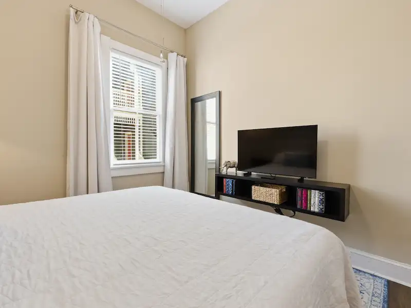 Suite 316A king bedroom at The Wilder House Savannah — tufted headboard premium white linens blue accent pillows natural light